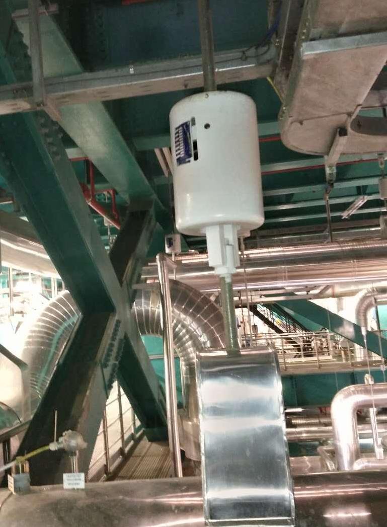 Variable spring hanger suspended from plant steel on a threaded rod, carrying an insulated line