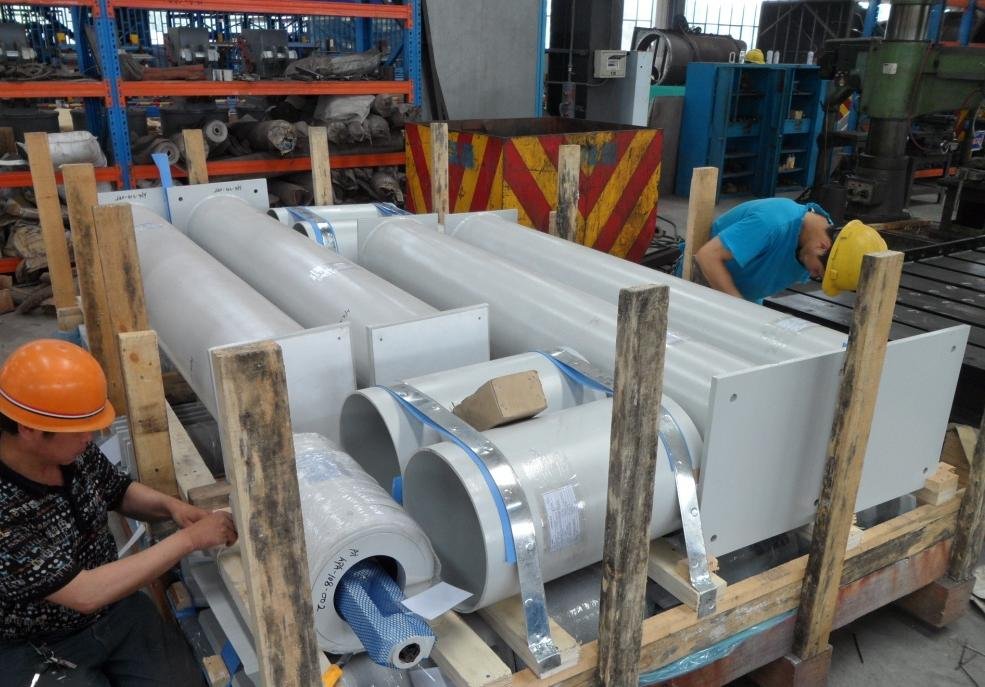 Workers securing large support units inside a braced crate frame at the packing area