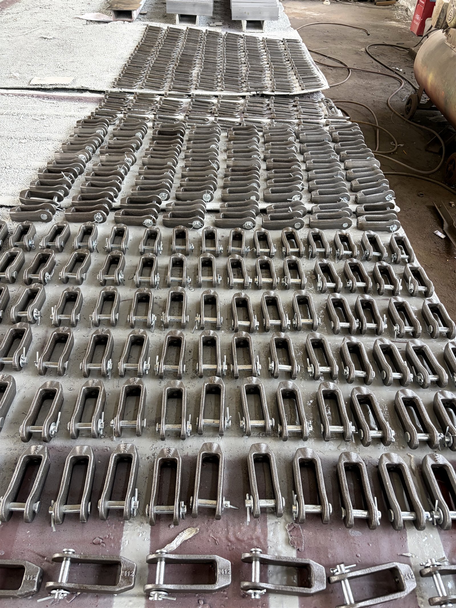Rows of forged clevis product-family components staged indoors at the manufacturing base
