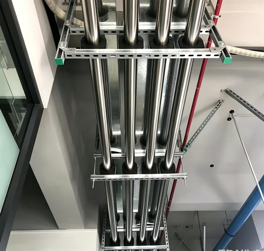Strut channel trapeze racks supporting stainless steel risers with insulated pipe clamps